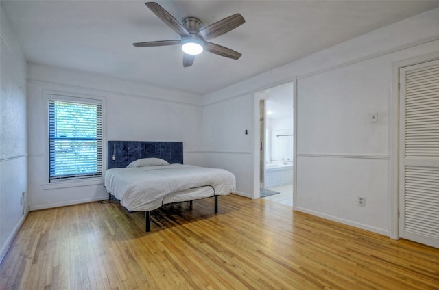 bedroom with light wood-type flooring, ceiling fan, and ensuite bath