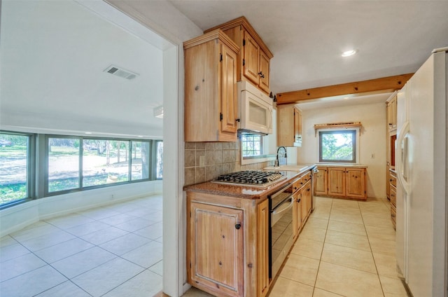 kitchen with sink, appliances with stainless steel finishes, decorative backsplash, and light tile patterned flooring