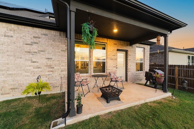 patio terrace at dusk with a lawn and an outdoor fire pit