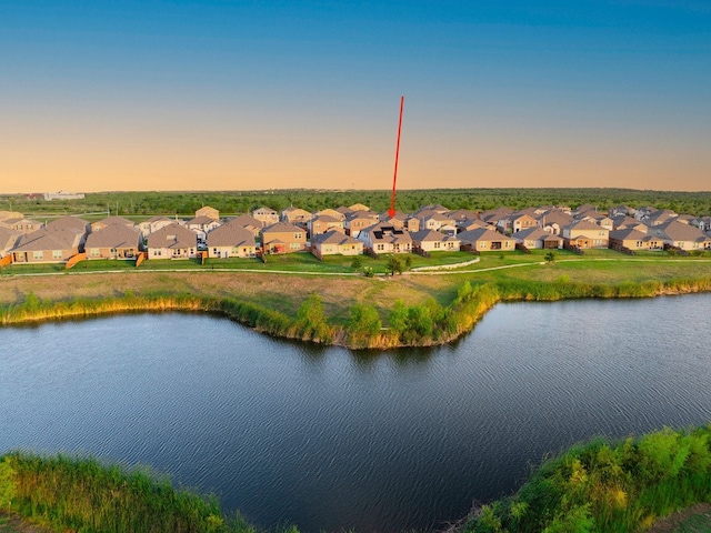 aerial view at dusk featuring a water view