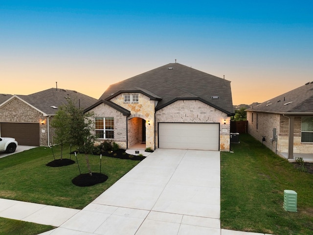 french country inspired facade with a yard and a garage