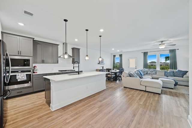 kitchen featuring gray cabinetry, stainless steel oven, hanging light fixtures, and built in microwave