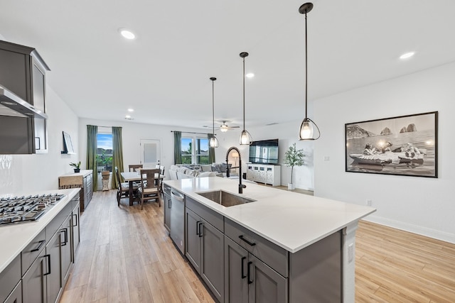 kitchen featuring ceiling fan, sink, hanging light fixtures, an island with sink, and appliances with stainless steel finishes