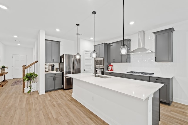 kitchen featuring decorative light fixtures, gray cabinets, stainless steel appliances, and wall chimney exhaust hood