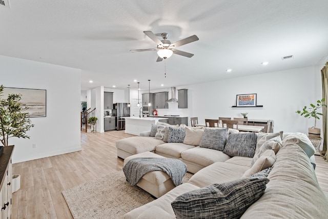 living room featuring ceiling fan, light hardwood / wood-style floors, and sink