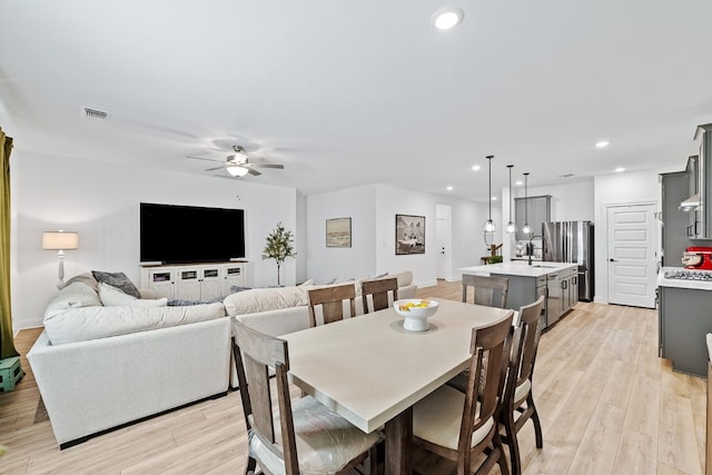 dining room with light wood-type flooring, ceiling fan, and sink