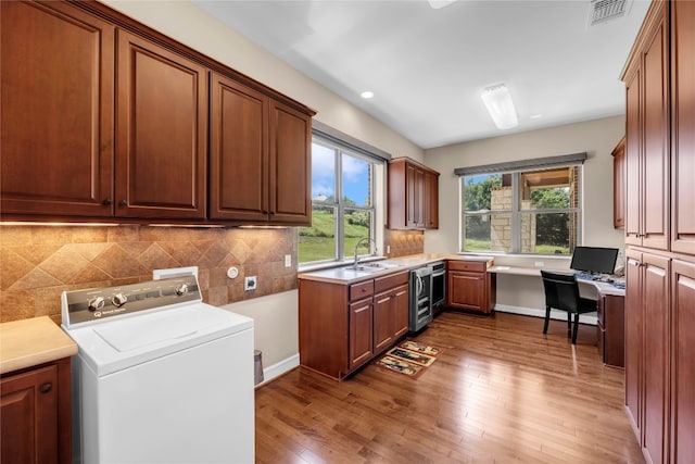 laundry area with washer / clothes dryer, sink, plenty of natural light, and hardwood / wood-style floors