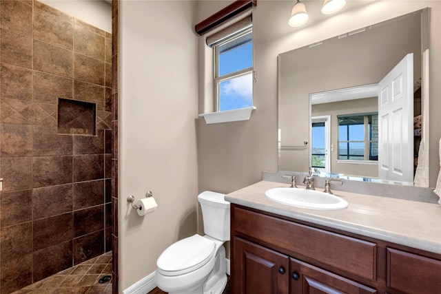 bathroom with tiled shower, vanity, and toilet