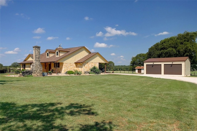 view of front of home featuring a garage, a front yard, and an outbuilding