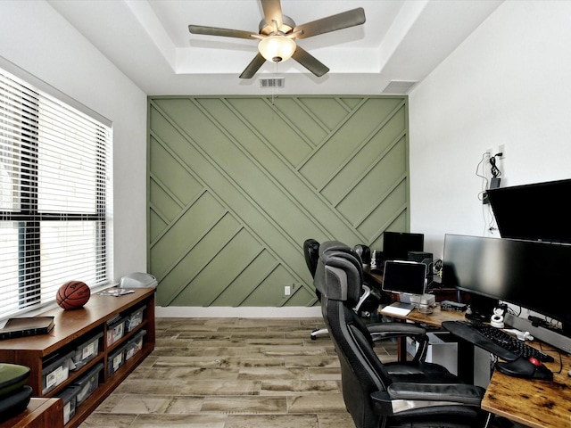 office area featuring a raised ceiling, ceiling fan, plenty of natural light, and light wood-type flooring