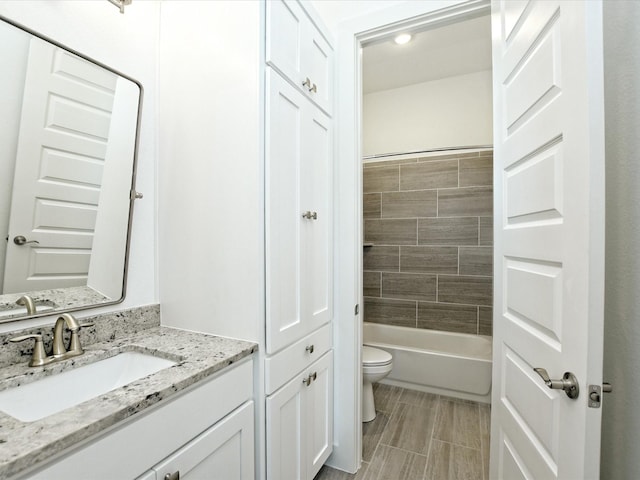 full bathroom featuring vanity, tiled shower / bath combo, and toilet