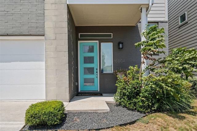 view of exterior entry featuring brick siding and concrete block siding