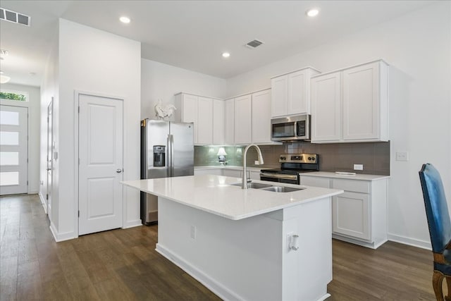 kitchen with appliances with stainless steel finishes, an island with sink, dark wood-type flooring, sink, and white cabinetry