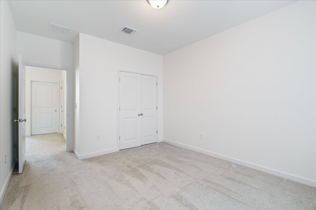 unfurnished bedroom with a closet and light carpet