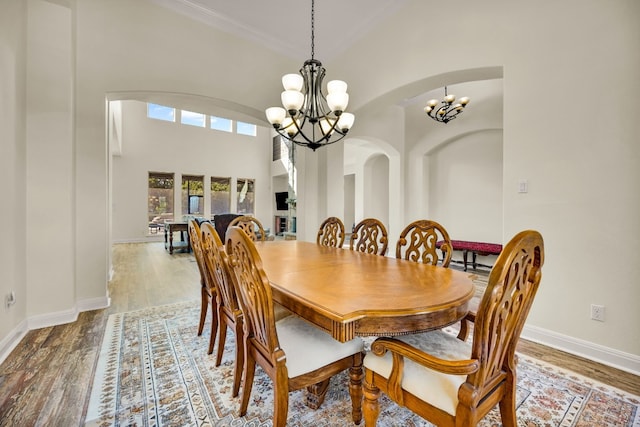 dining space featuring a notable chandelier, a towering ceiling, and hardwood / wood-style flooring