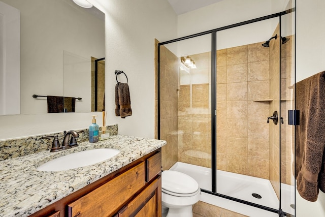 bathroom featuring a shower with shower door, vanity, and toilet