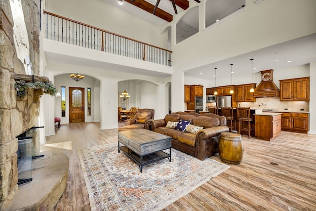 living room with light hardwood / wood-style floors, a fireplace, a chandelier, and a high ceiling