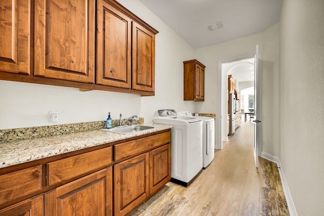 laundry area with cabinets, light hardwood / wood-style floors, separate washer and dryer, and sink