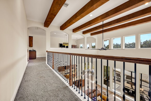 hall featuring beamed ceiling and carpet flooring