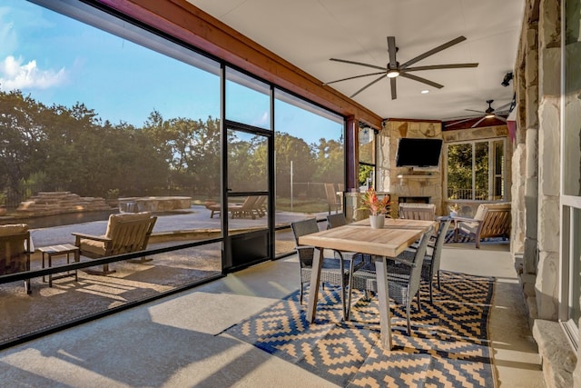 sunroom / solarium featuring ceiling fan and an outdoor stone fireplace