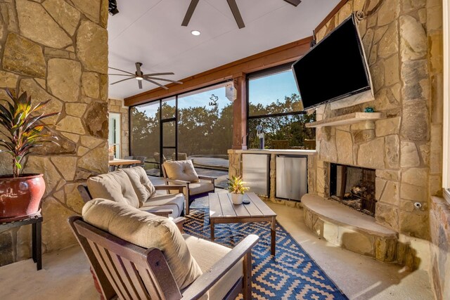 living room featuring ceiling fan and a stone fireplace