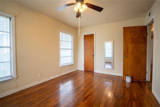 unfurnished bedroom featuring multiple windows, dark hardwood / wood-style flooring, and ceiling fan