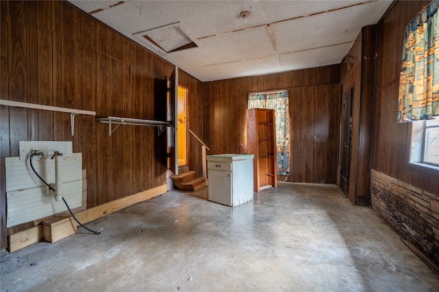 empty room featuring wood walls and concrete floors