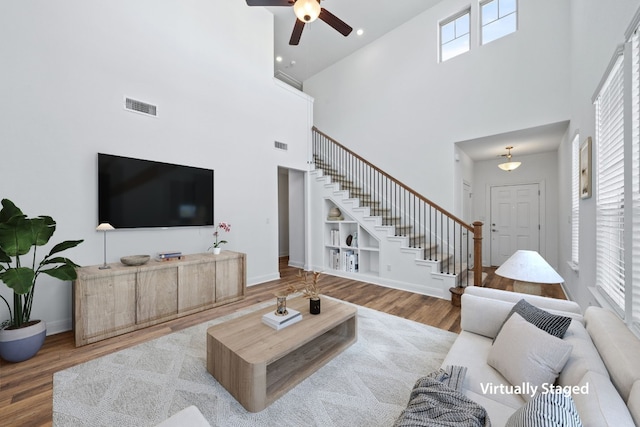 living room featuring ceiling fan, a towering ceiling, and hardwood / wood-style flooring