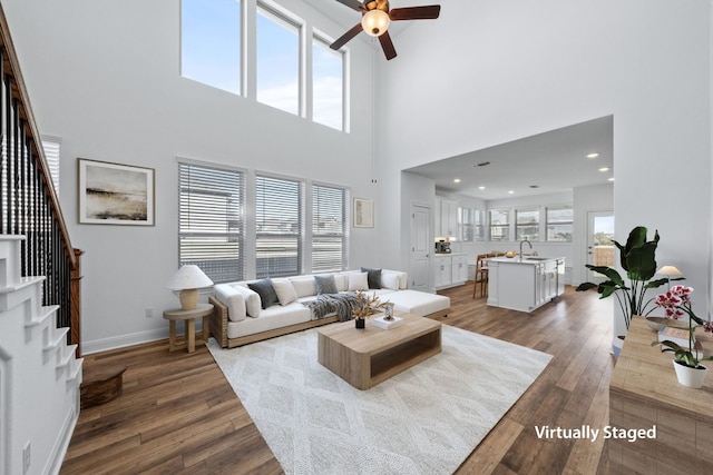 living room featuring ceiling fan, sink, dark wood-type flooring, and a high ceiling