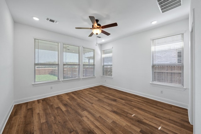 spare room with dark wood-type flooring, ceiling fan, and a healthy amount of sunlight