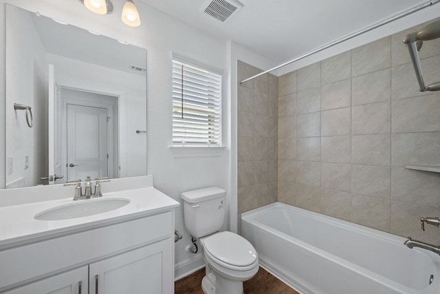 full bathroom with vanity, hardwood / wood-style floors, tiled shower / bath combo, and toilet