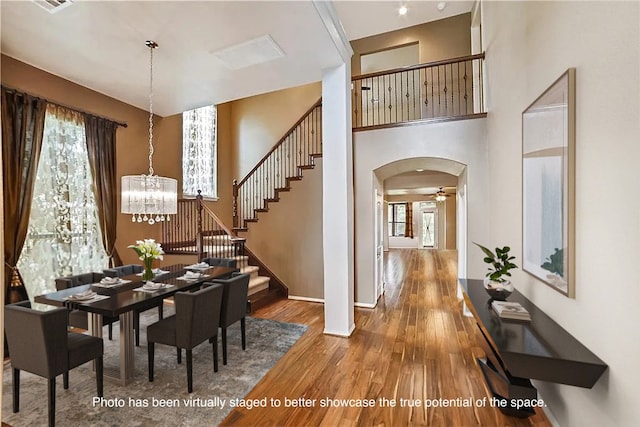 dining space with a high ceiling, wood-type flooring, and a notable chandelier