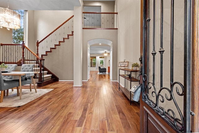 foyer entrance with hardwood / wood-style flooring, a high ceiling, and an inviting chandelier