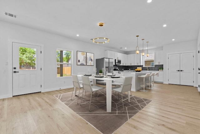 dining space featuring light wood-type flooring and an inviting chandelier