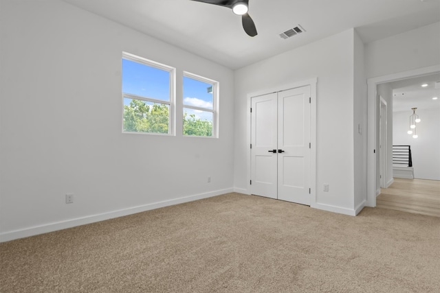 unfurnished bedroom featuring ceiling fan, a closet, and light carpet