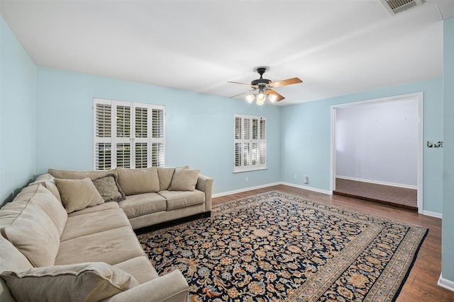 living room featuring ceiling fan and dark wood-type flooring