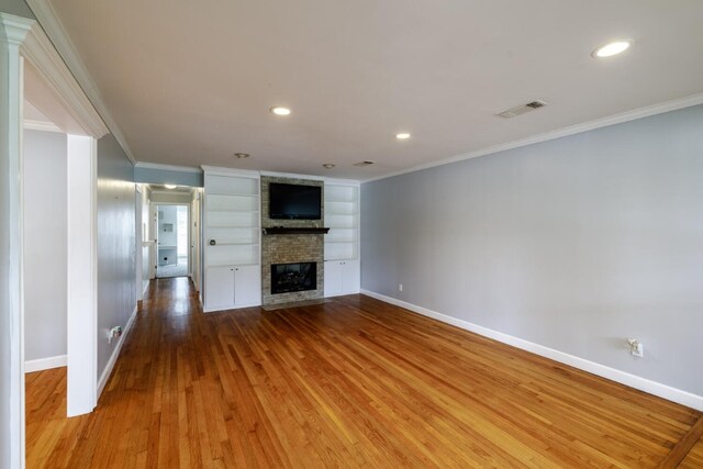 unfurnished living room featuring ornamental molding, a brick fireplace, and wood-type flooring