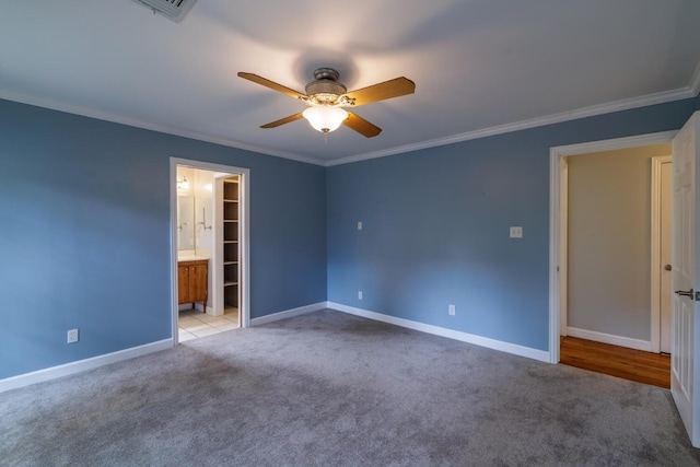 unfurnished bedroom with crown molding, light colored carpet, a spacious closet, ceiling fan, and connected bathroom