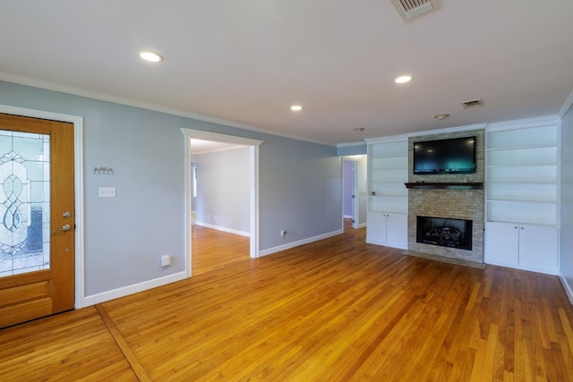 unfurnished living room featuring built in features, a fireplace, light hardwood / wood-style floors, and ornamental molding