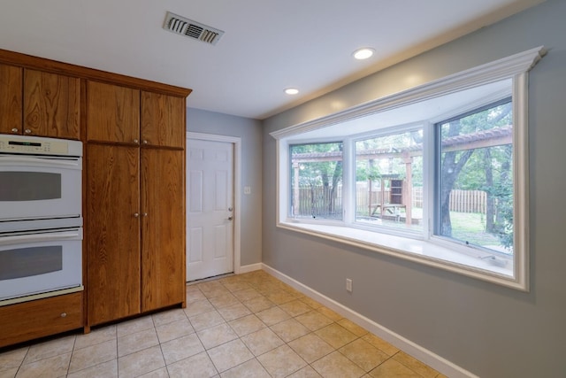 kitchen with white double oven and light tile patterned flooring