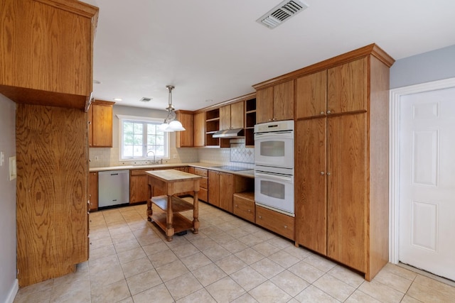 kitchen featuring pendant lighting, dishwasher, white double oven, sink, and decorative backsplash