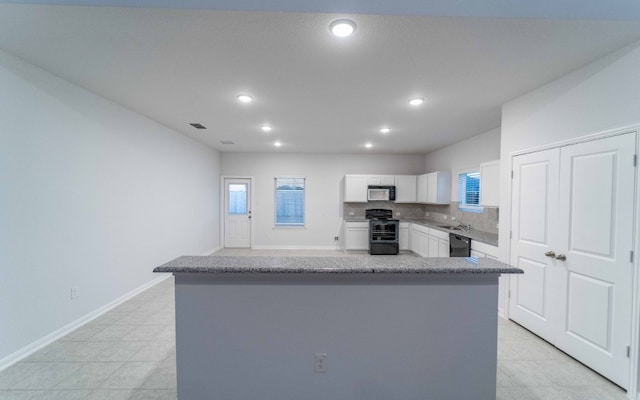 kitchen with black appliances, backsplash, a center island, and white cabinets