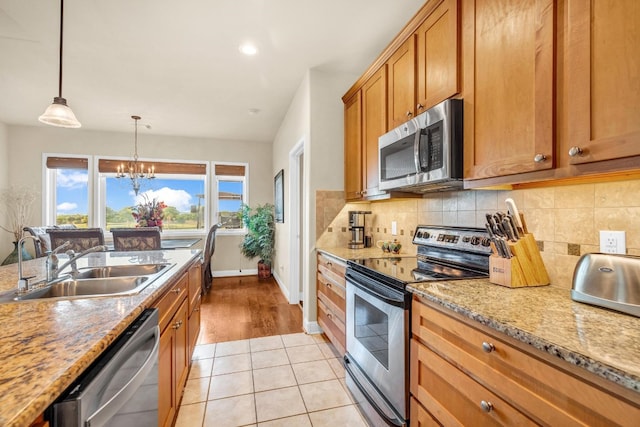 kitchen featuring appliances with stainless steel finishes, decorative light fixtures, sink, an inviting chandelier, and light hardwood / wood-style flooring