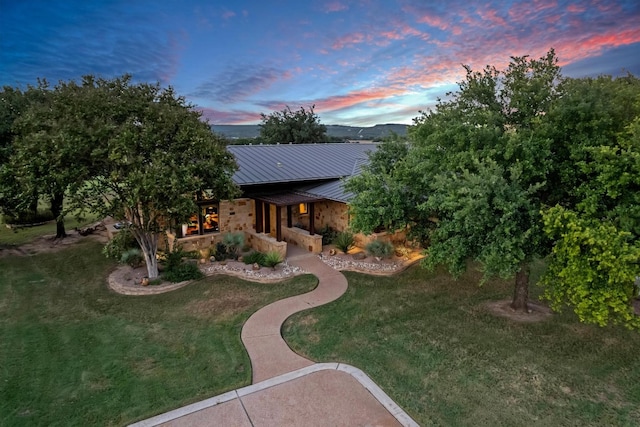 back house at dusk featuring a lawn