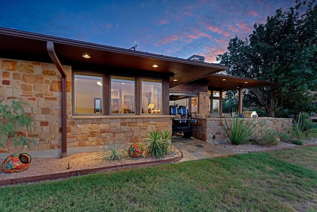 back house at dusk featuring a lawn