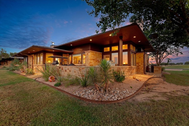 property exterior at dusk with cooling unit and a yard