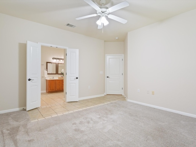 unfurnished bedroom featuring ceiling fan, light carpet, and ensuite bath