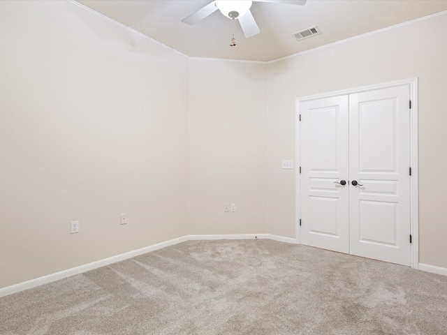 carpeted spare room featuring ceiling fan and crown molding