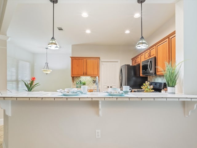 kitchen with stainless steel fridge, decorative light fixtures, a kitchen breakfast bar, decorative backsplash, and black / electric stove