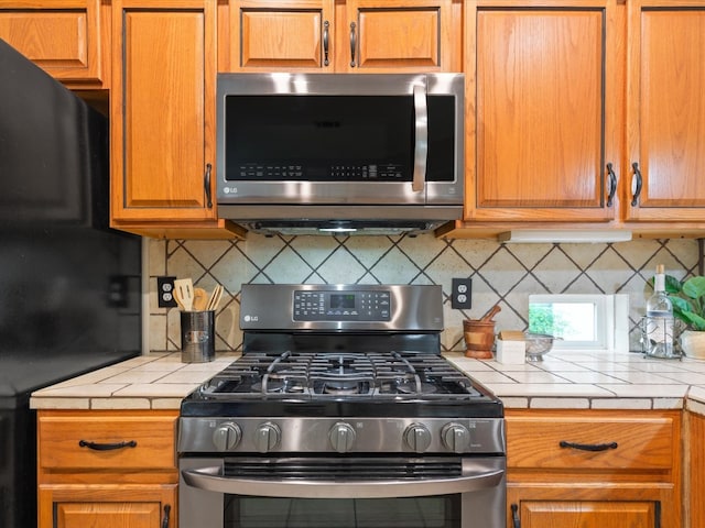 kitchen featuring appliances with stainless steel finishes, tile counters, and tasteful backsplash